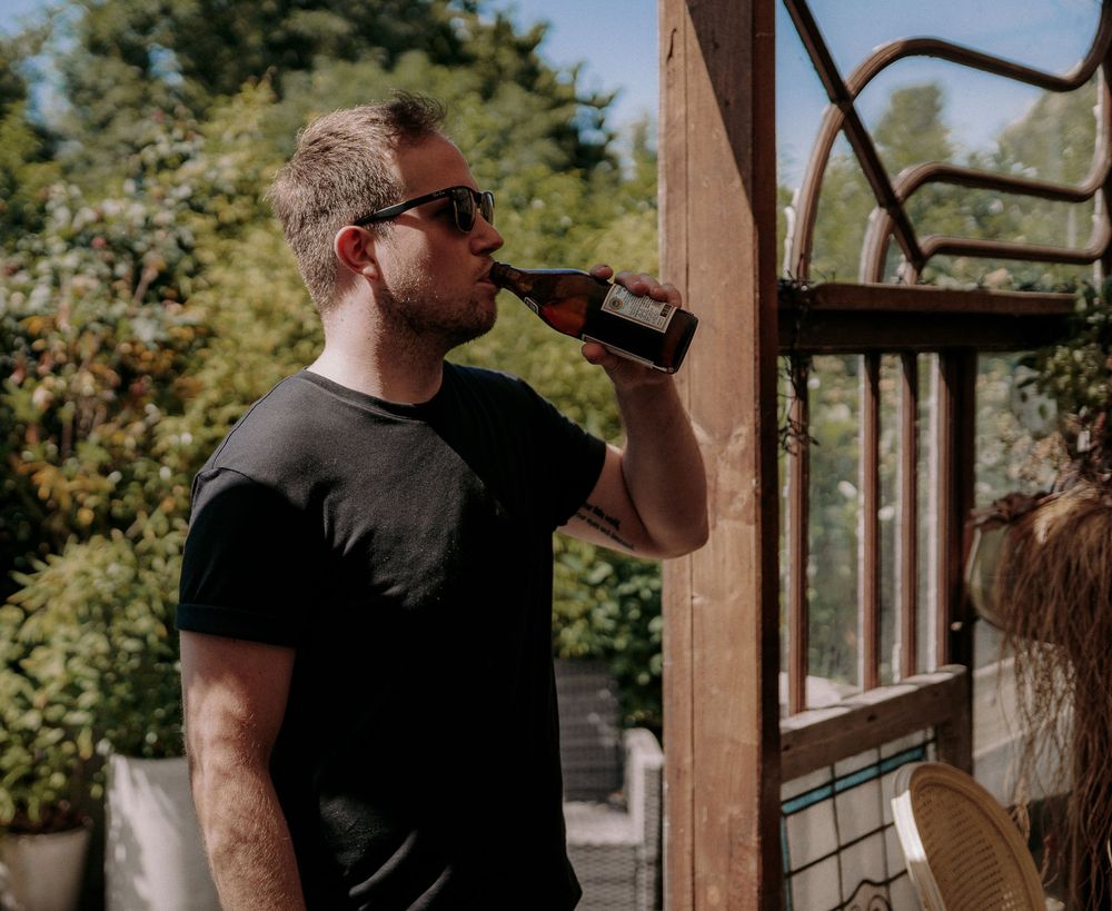 Person drinking from water bottle outdoors on sunny day.