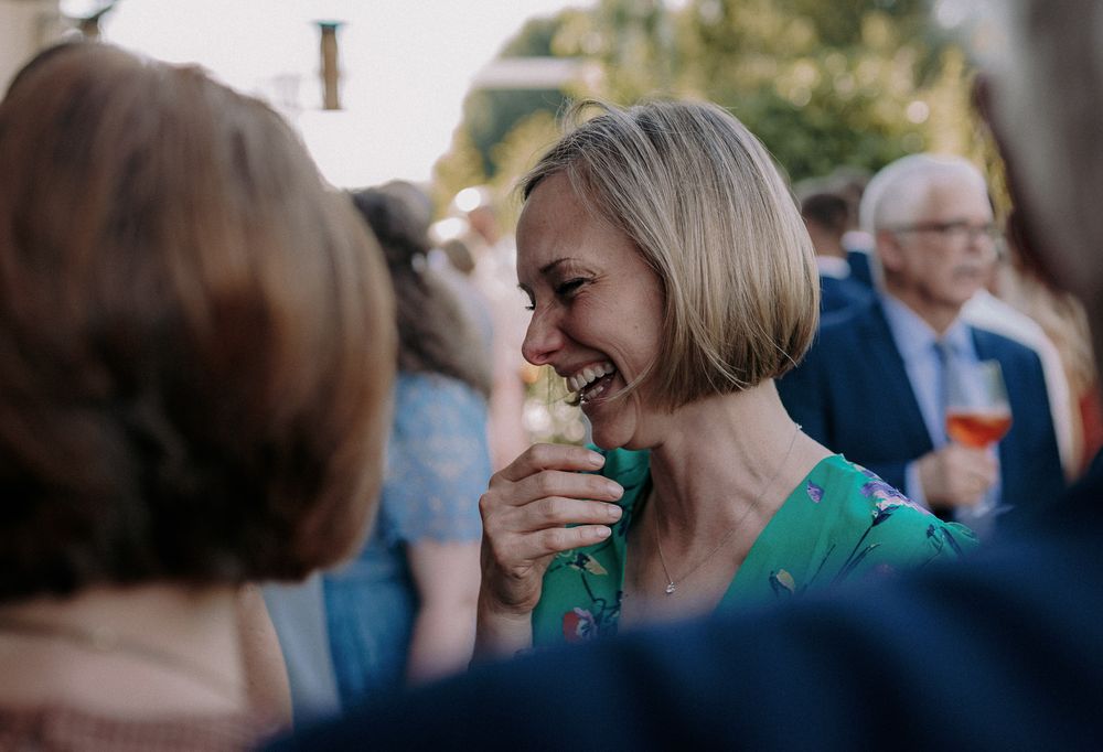 A person in a green dress laughing joyfully at an outdoor party.