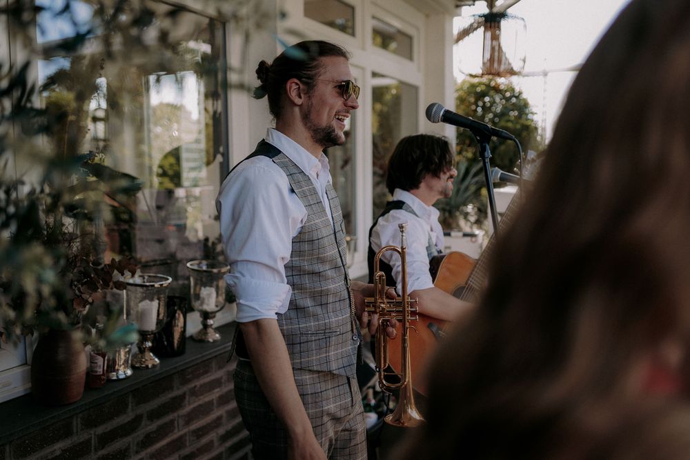 A person in a vest and rolled sleeves standing at an outdoor venue.