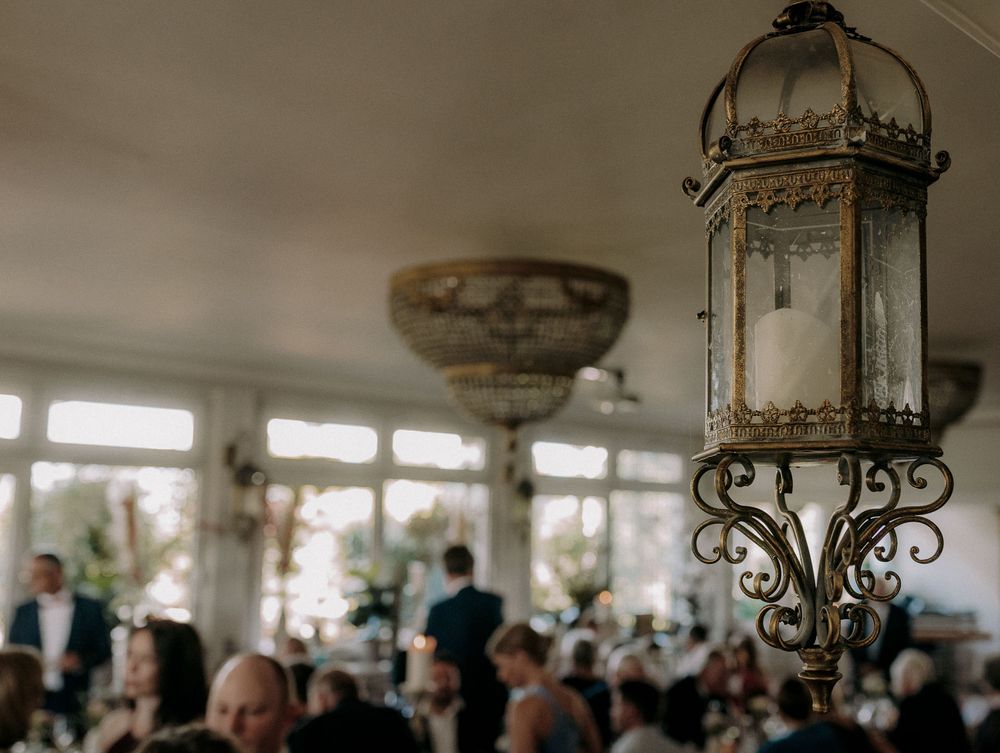 Elegant vintage lantern hanging in a crowded reception venue with soft lighting and atmospheric ambiance.