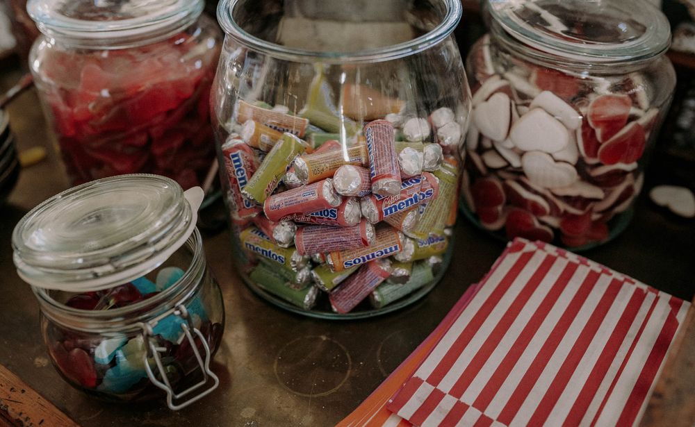 Glass jars filled with colorful candies and treats on display at a party.