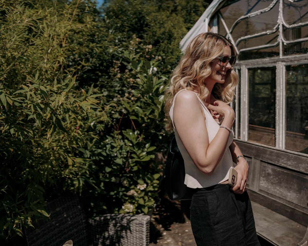 Casual outdoor portrait near greenhouse in garden setting.