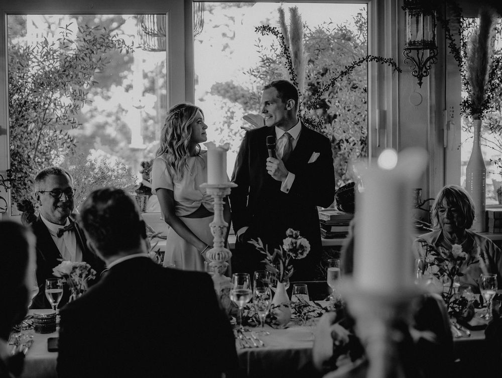 Black and white photo of guests celebrating during a speech at an elegant reception.