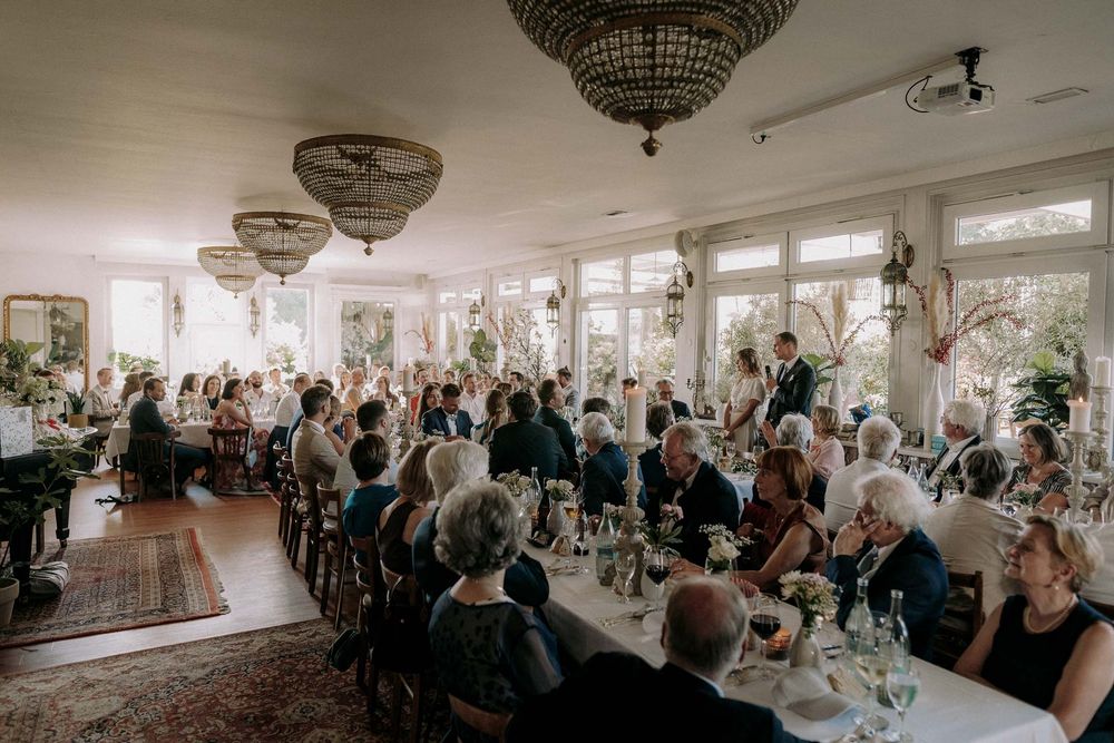 Elegant wedding reception venue with ornate chandeliers and tables filled with celebrating guests.