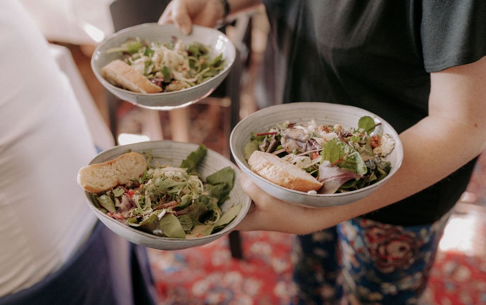 Fresh salads being served on plates at an upscale event.