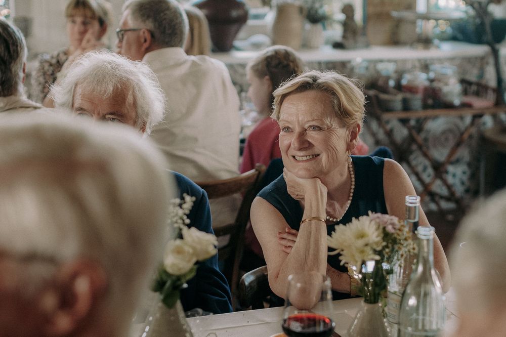 A guest at an elegant reception rests her chin on her hand while smiling warmly.