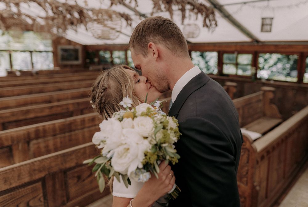Intimate wedding moment shared between couple in wooden chapel.