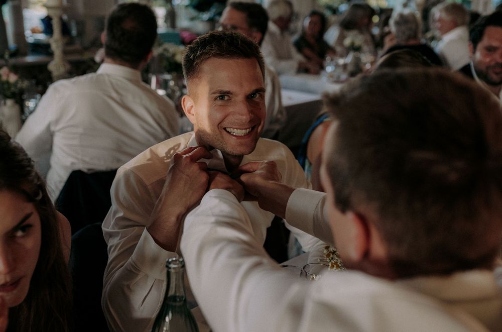 A celebratory moment during a wedding reception with guests interacting across a dining table.