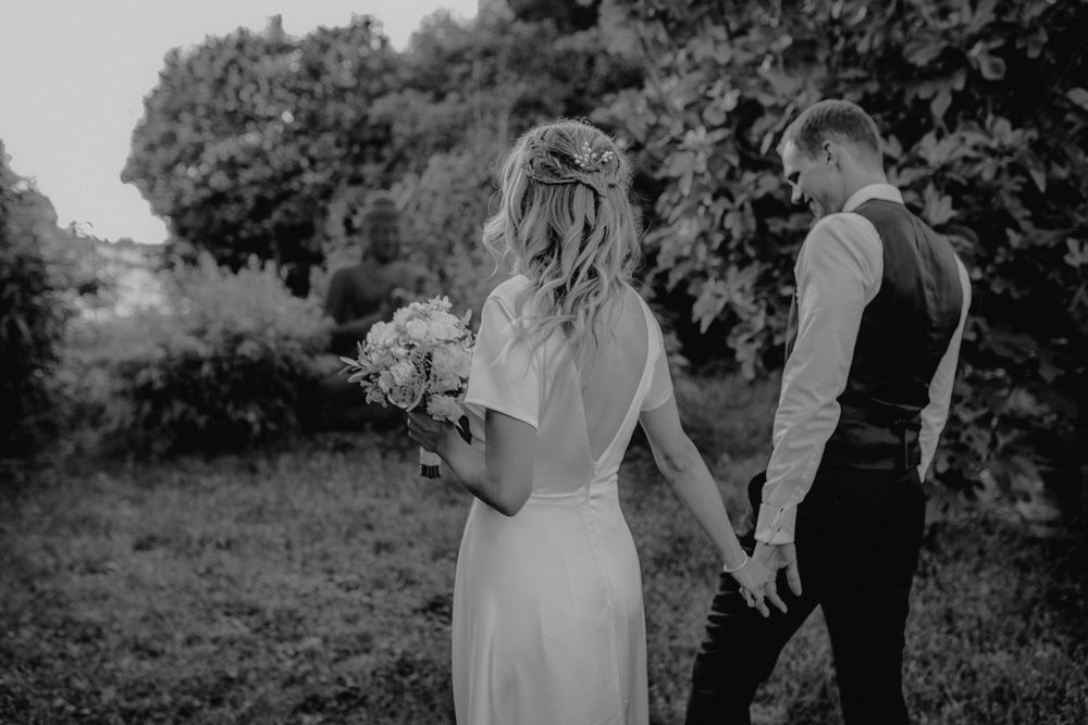 Black and white photo of newlyweds in a garden setting with the bride holding a bouquet.