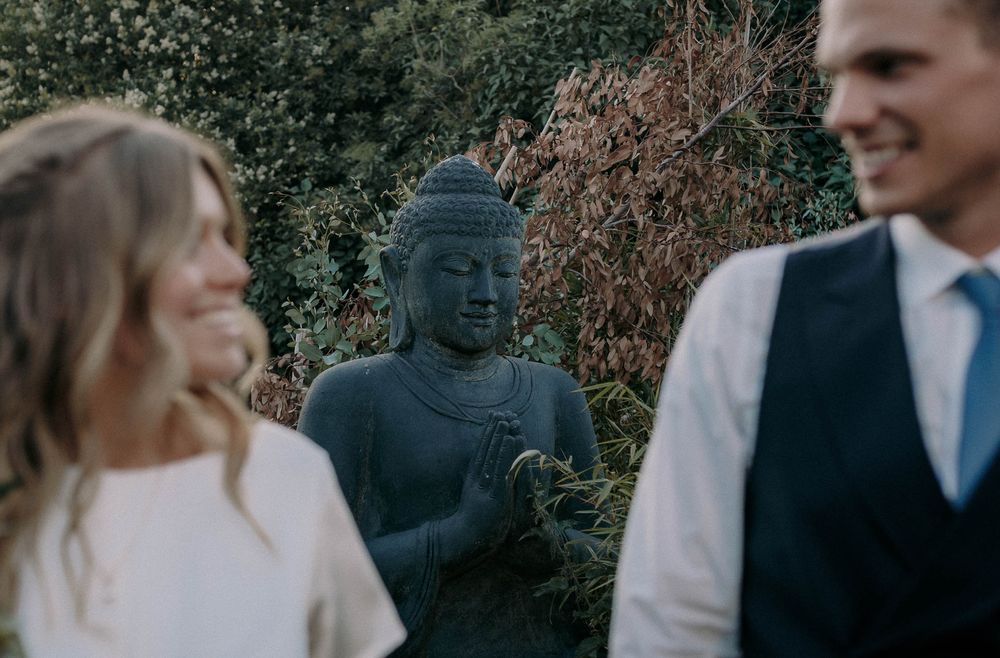 A garden wedding scene featuring a Buddha statue among greenery.