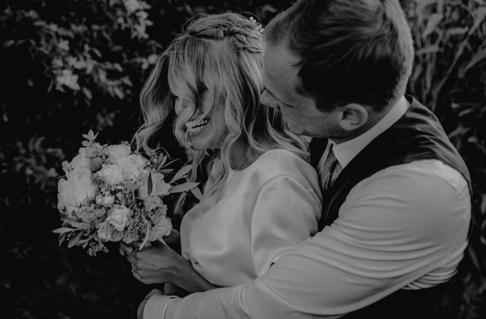 Black and white portrait of a wedding couple sharing an intimate moment with flowers.