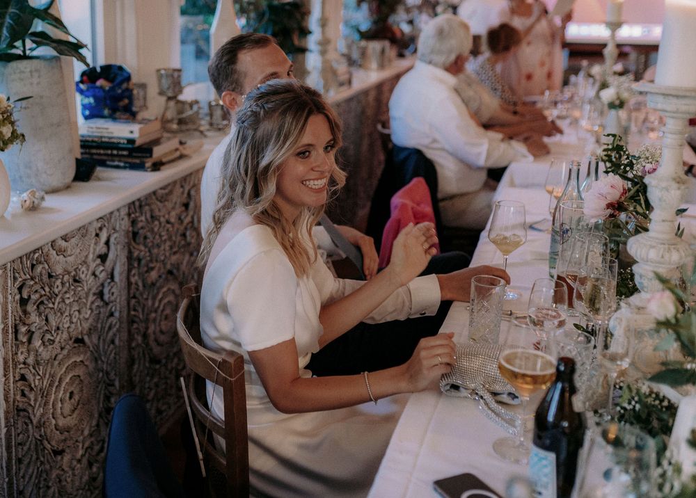 Guests enjoying themselves at an elegant wedding reception with decorative table settings and floral arrangements.