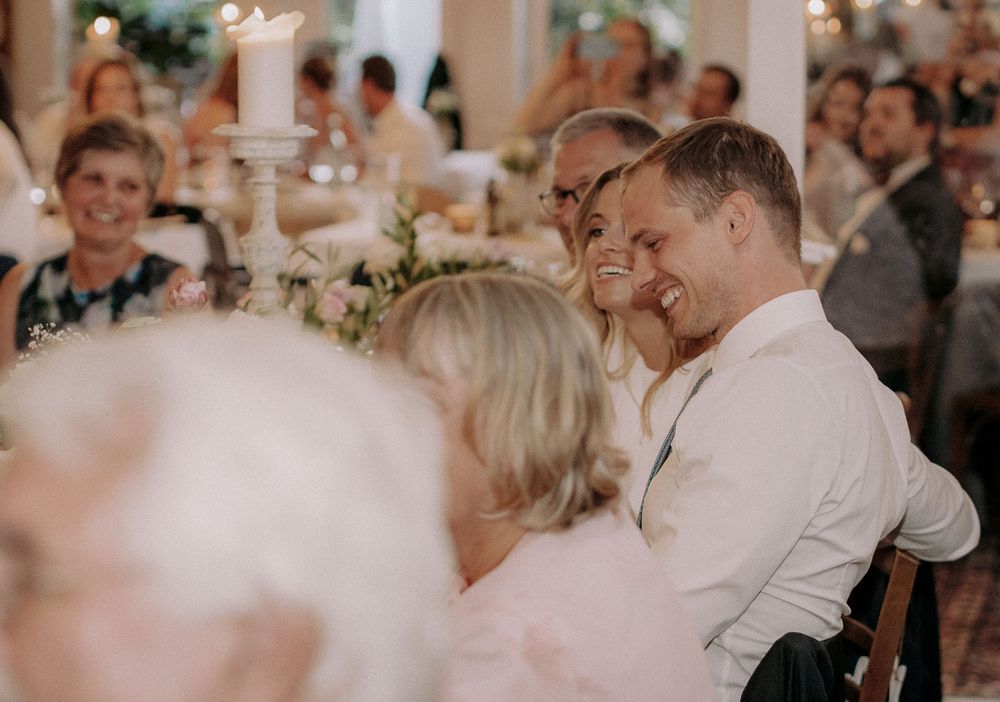 Wedding guests sharing a joyful moment during a reception with candlelit table settings.