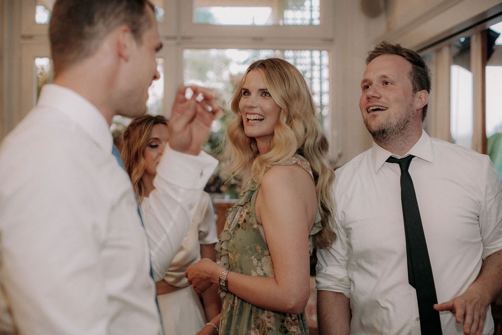 Wedding celebration candid moment with guests laughing and socializing in formal attire.