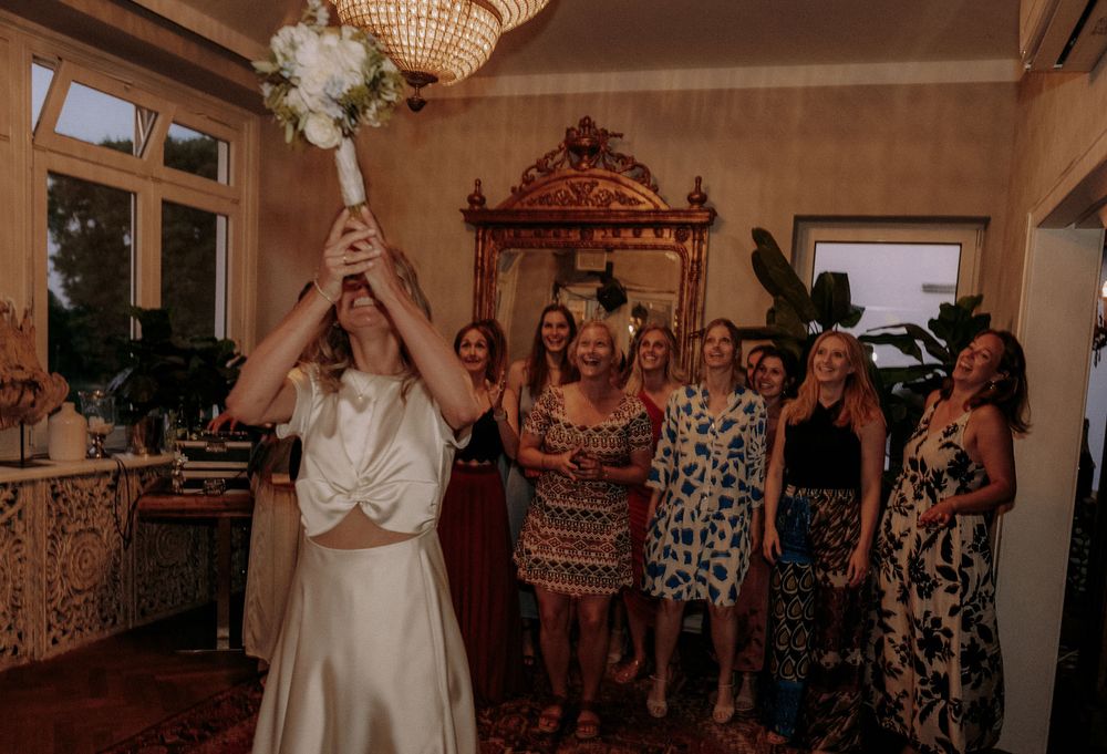 A bouquet toss moment at a wedding reception with guests watching in anticipation.