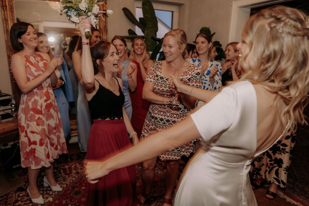 Wedding guests share a joyful moment during reception festivities under a crystal chandelier.