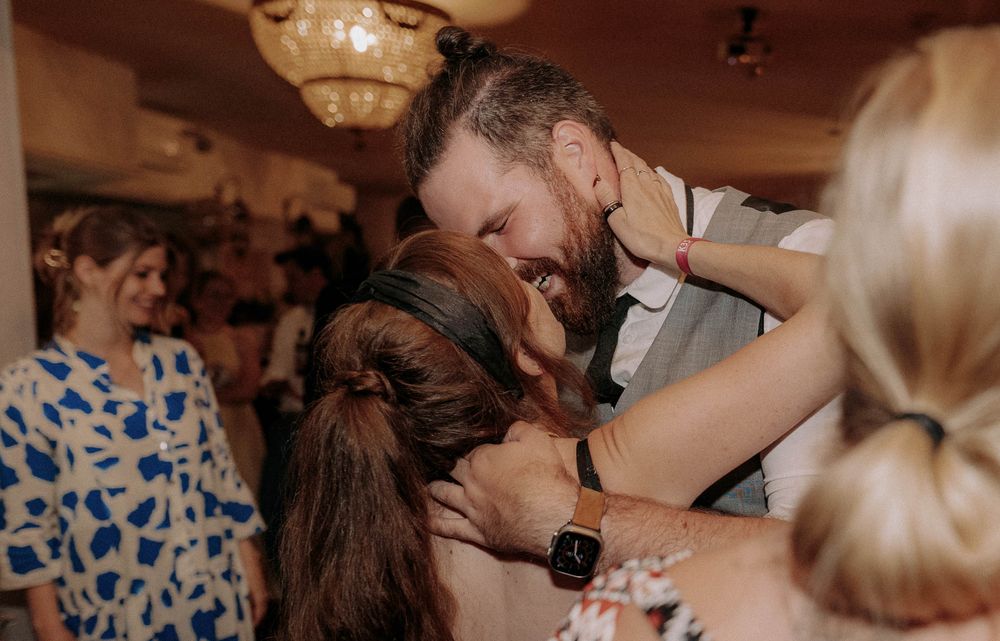 A romantic dance moment at a wedding reception with guests in floral dresses watching.