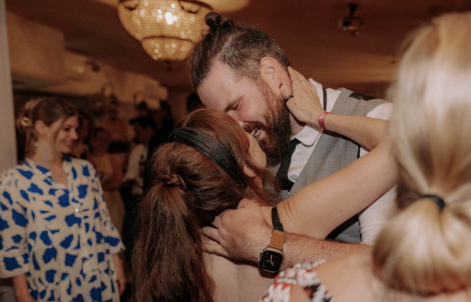 A romantic dance moment at a wedding reception with guests in floral dresses watching.
