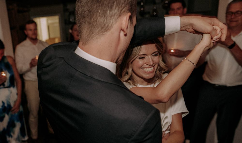 A couple sharing a dance at their wedding reception while guests look on with phones recording.