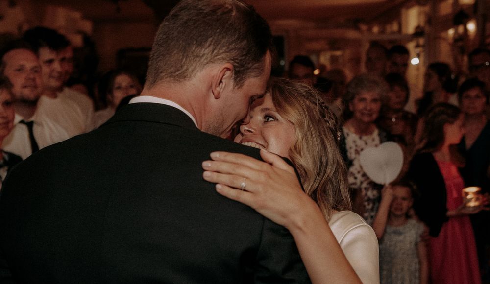 Intimate moment between couple dancing at dimly lit reception.