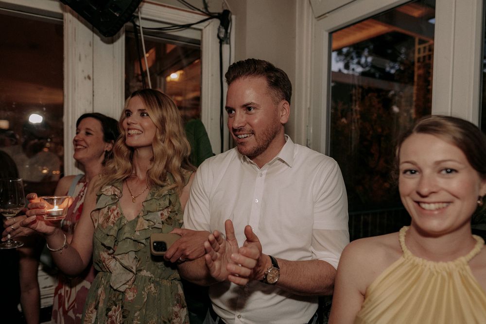 Wedding guests celebrating with drinks and laughter at an indoor reception party.