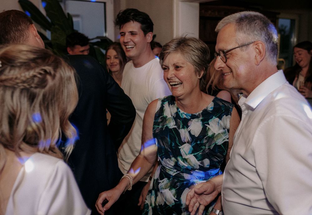 Wedding guests enjoying themselves and dancing at an indoor celebration.