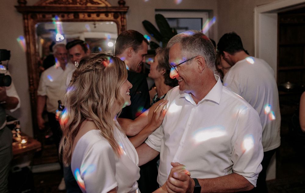 Couples dancing together at an indoor party with decorative lighting.