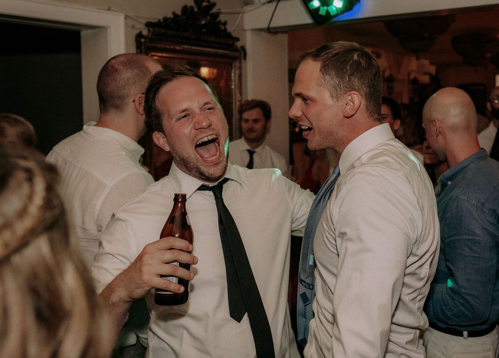 Friends sharing laughs and drinks during lively wedding reception.