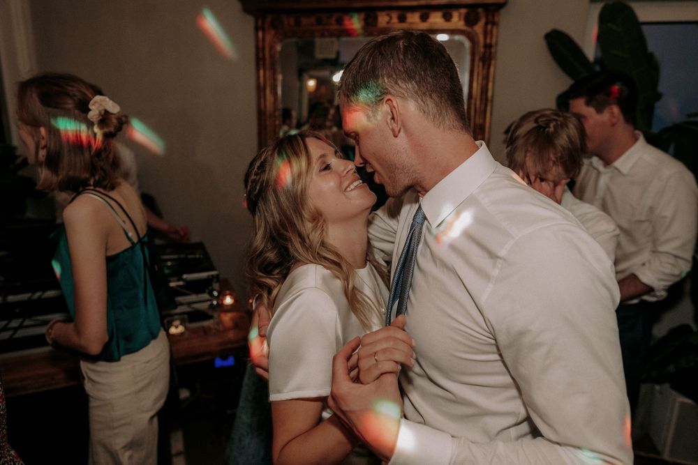 Couple sharing intimate dance under party lights at reception.