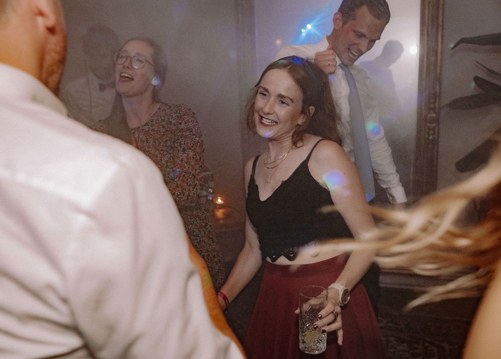 People dancing and laughing at an indoor party with dim lighting and festive atmosphere.