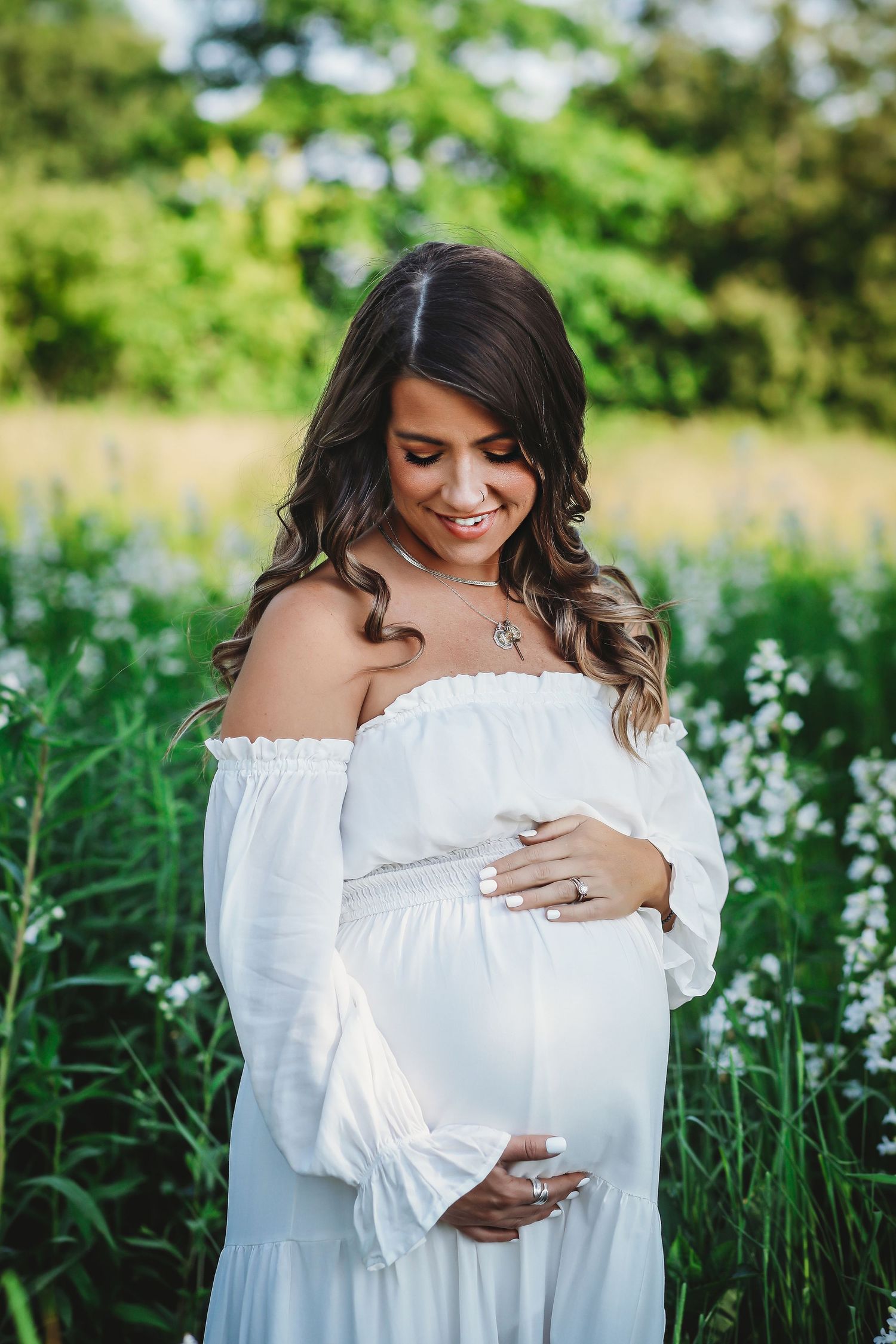 Mom at maternity session holding her belly in a flower field