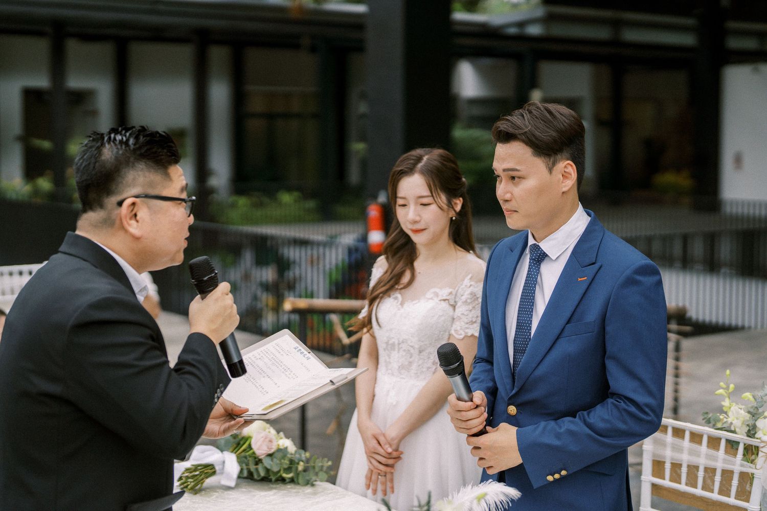Elegant outdoor wedding ceremony with floral decorations and white chairs arranged in a garden setting.