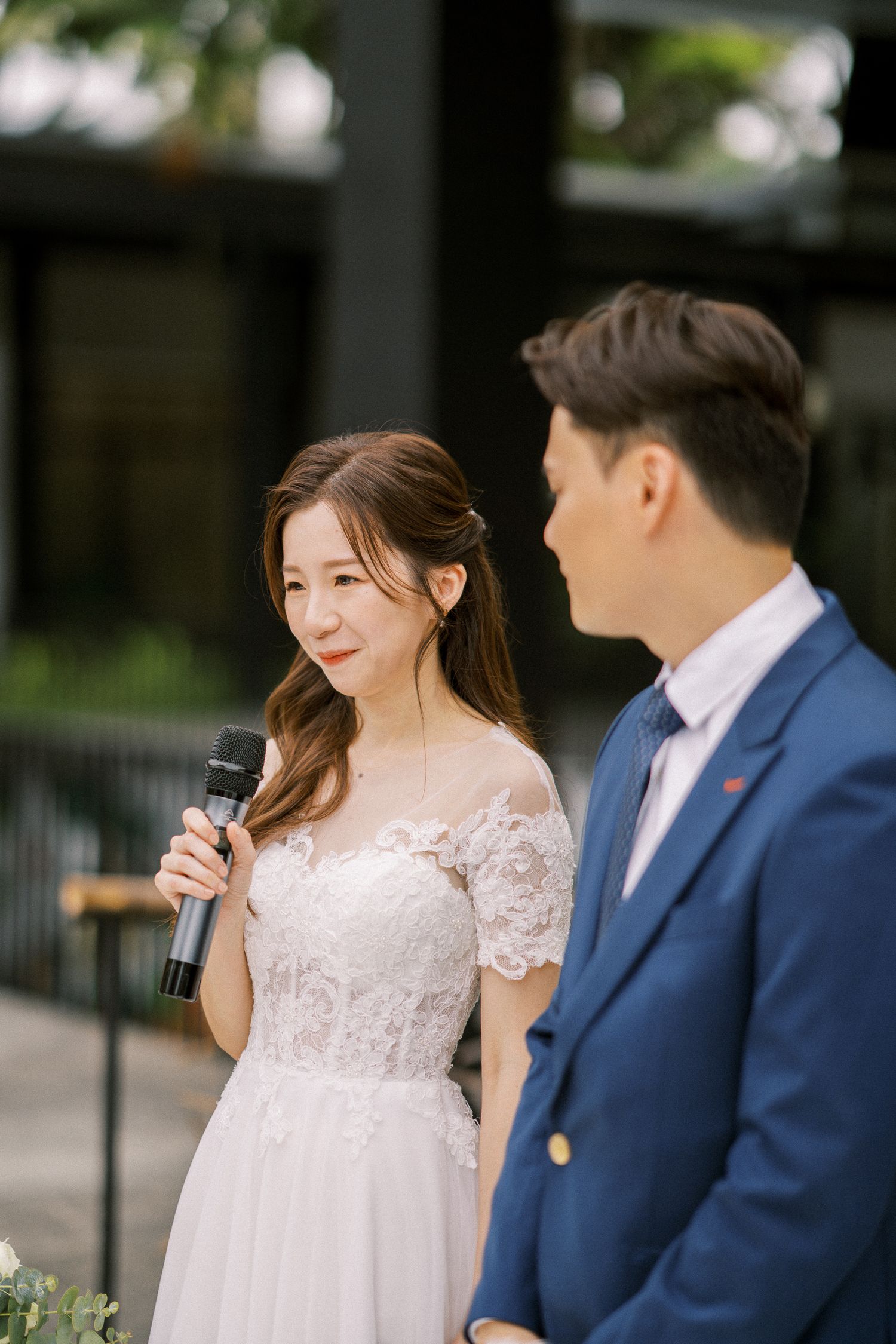 Wedding couple exchanging vows at an intimate outdoor ceremony with lush greenery in the background.