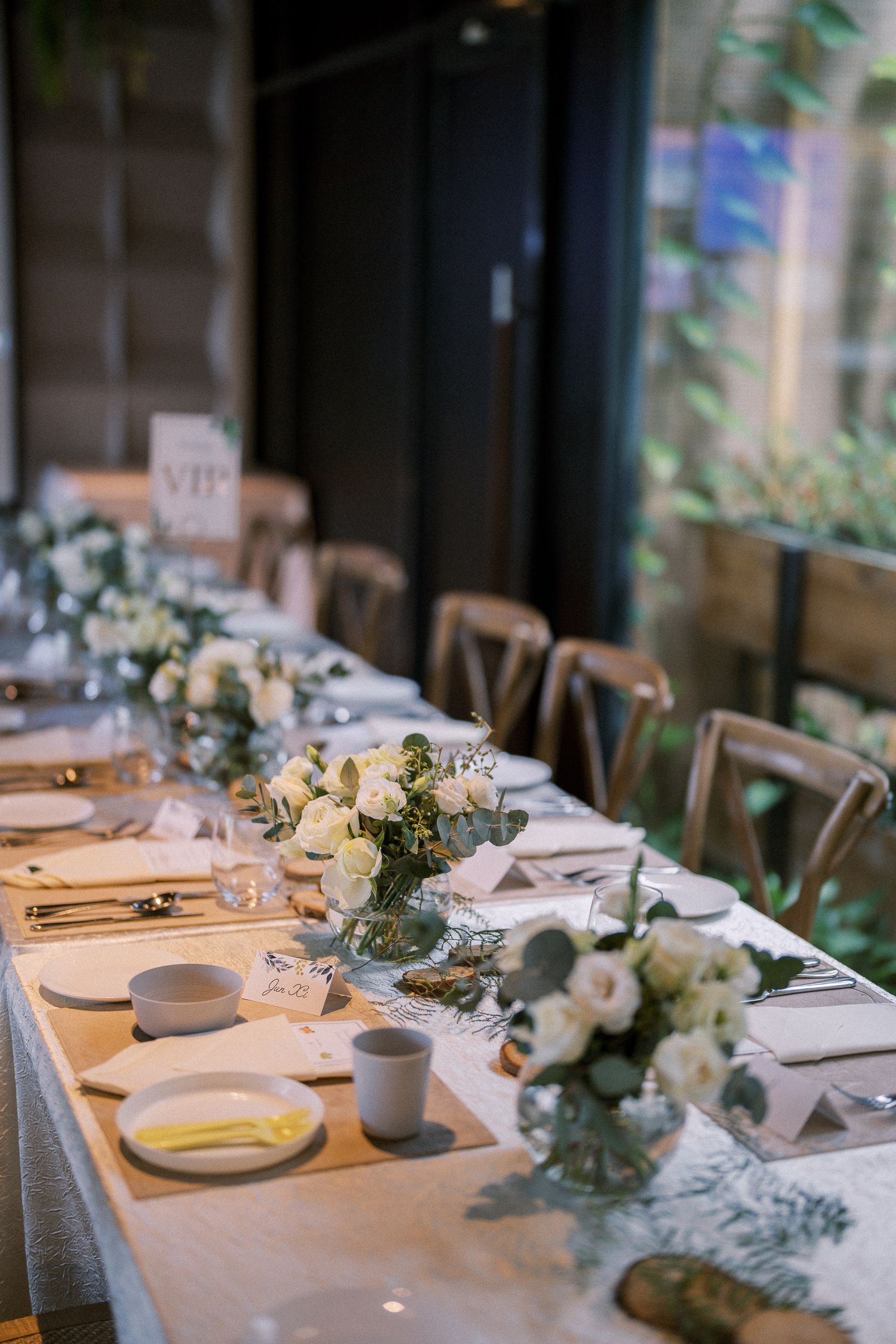 An elegant wedding reception table setting with white linens and delicate floral centerpieces.