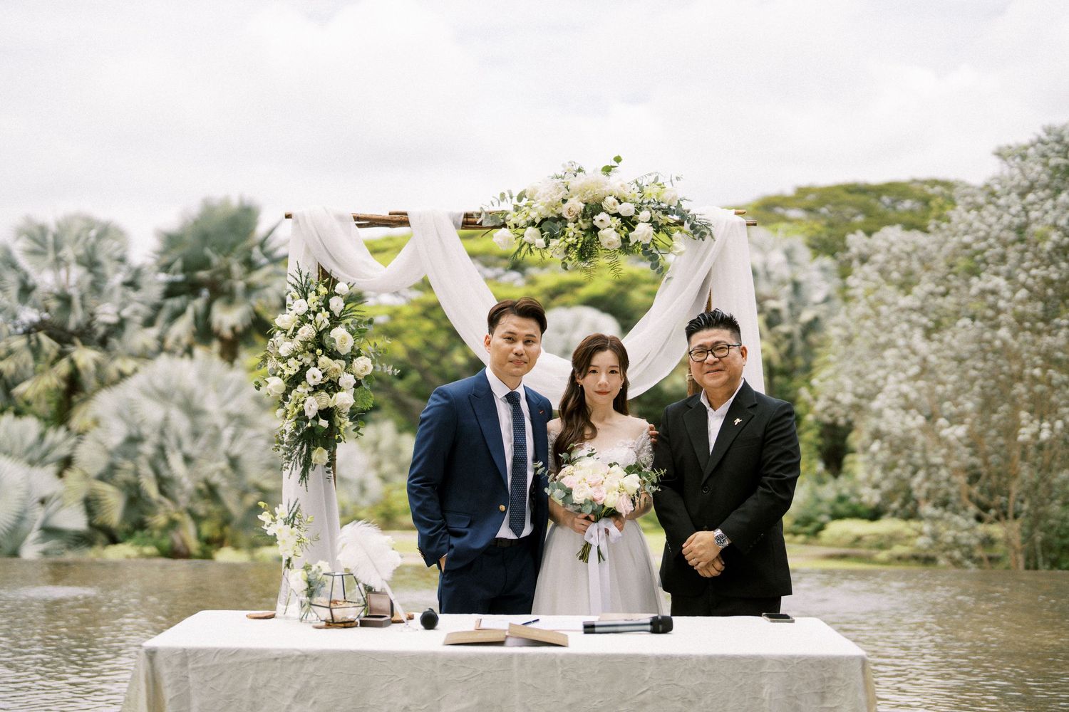 Outdoor wedding ceremony with white floral arrangements and natural garden backdrop.