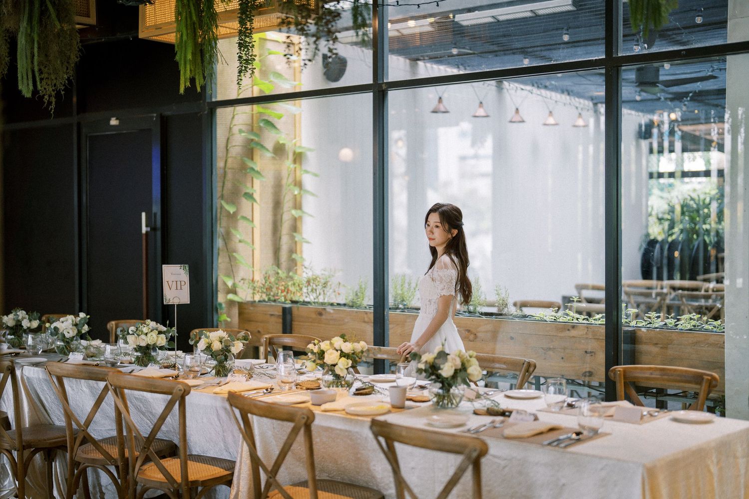 Elegant wedding reception venue with rustic wooden chairs and white tablecloths set for dining.