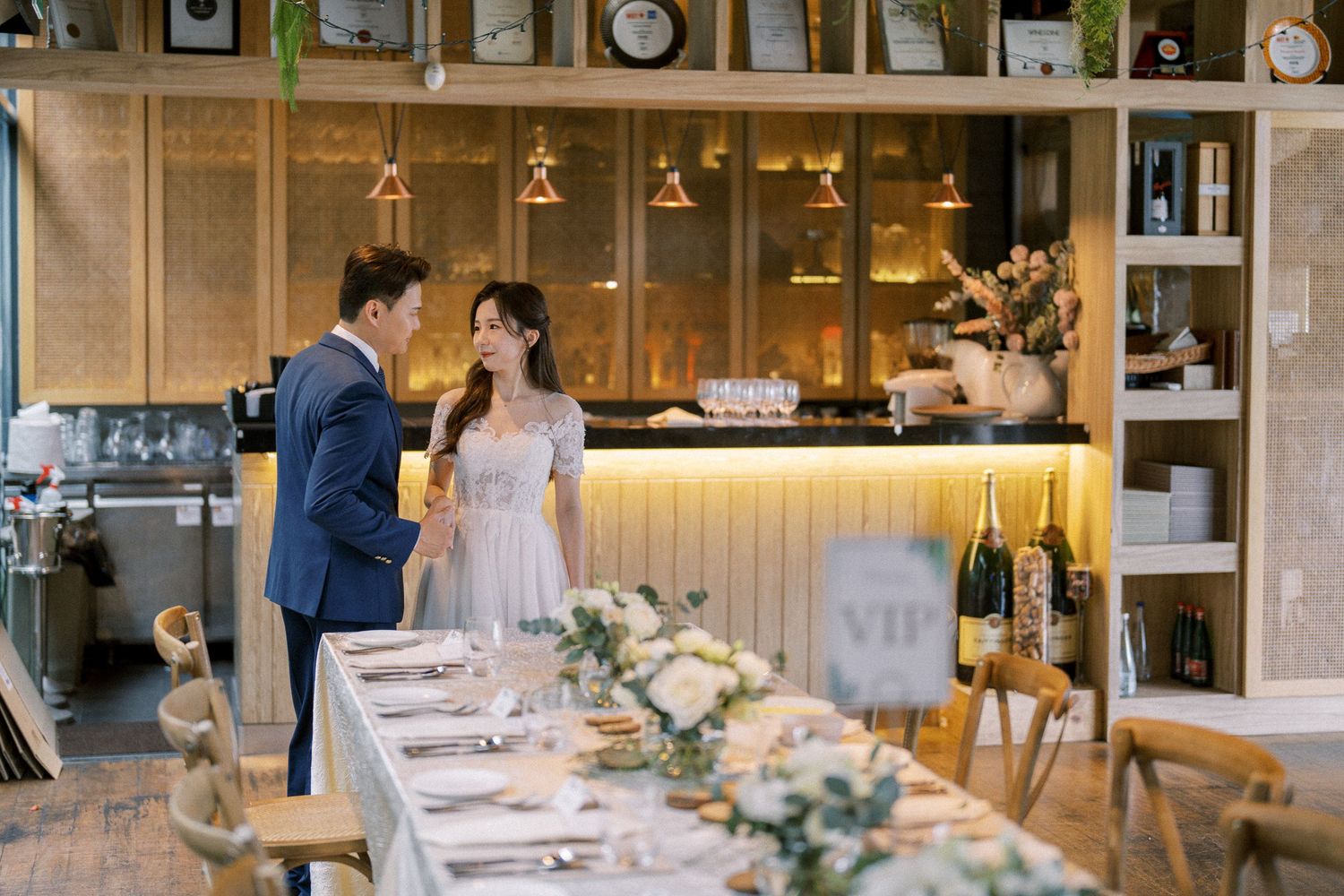Long banquet tables set with elegant place settings and floral arrangements in a modern restaurant space.