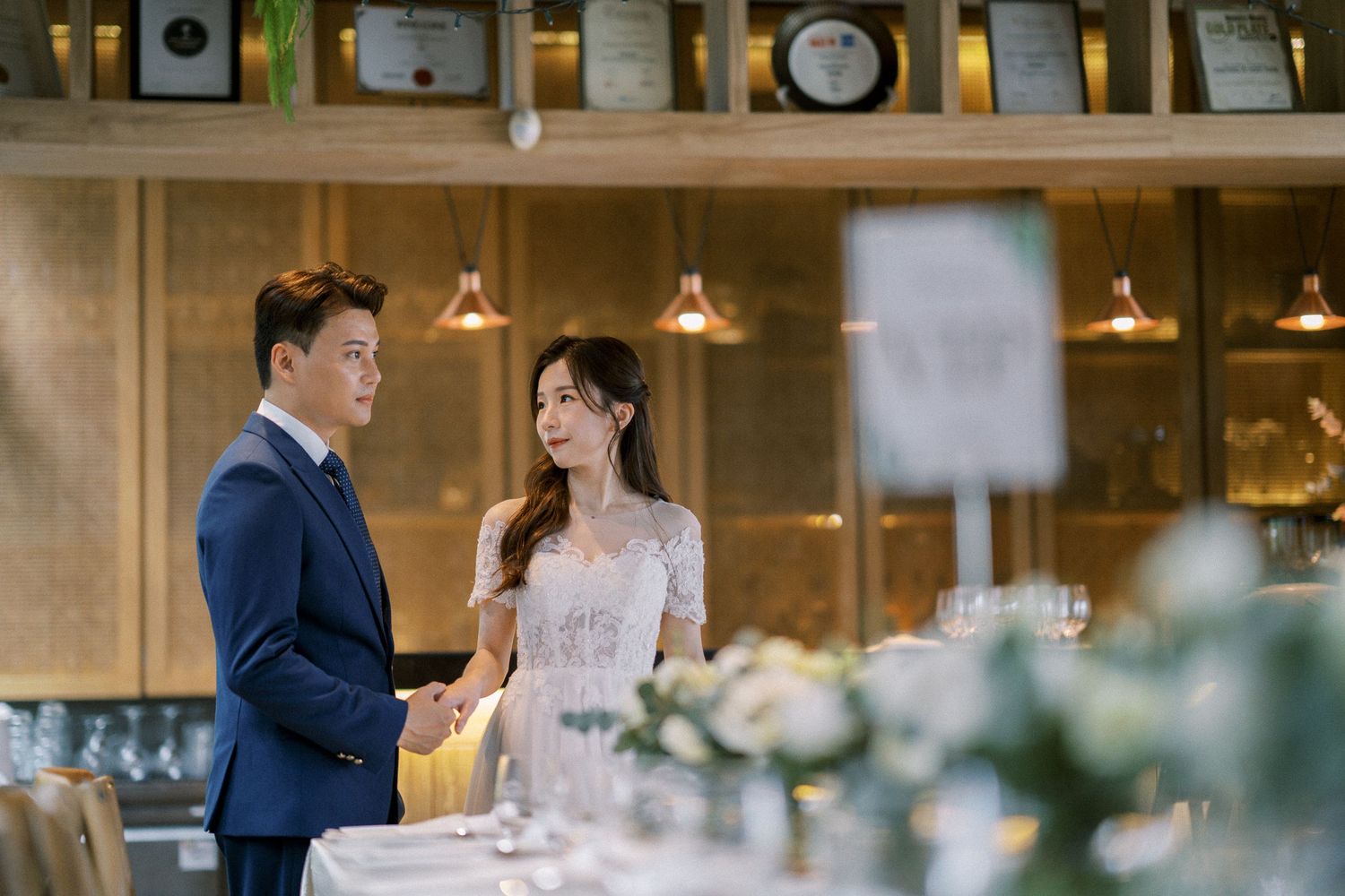 An indoor wedding reception venue with warm lighting and elegant table settings.