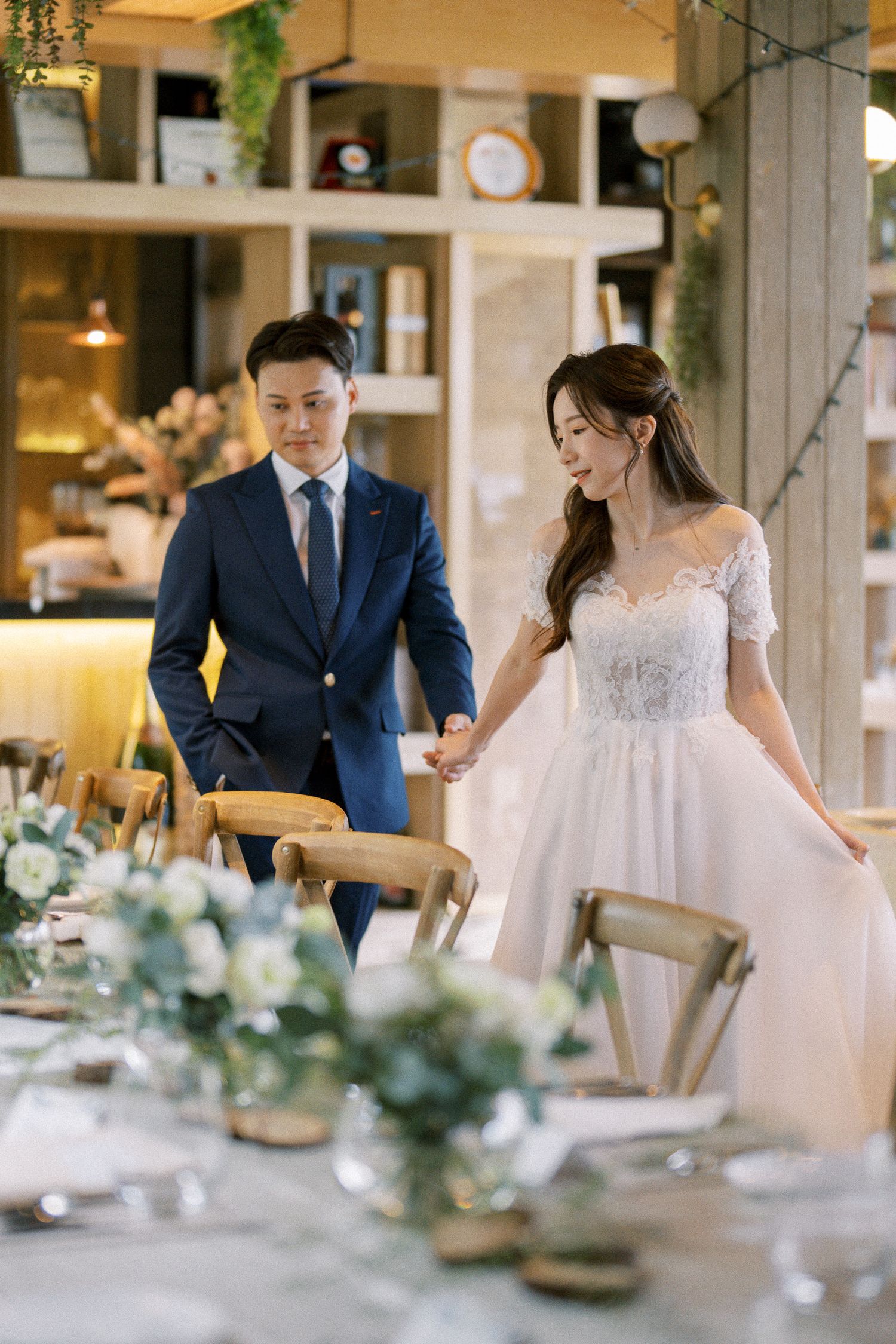 Wedding reception tables decorated with greenery and white floral centerpieces in a bright indoor space.