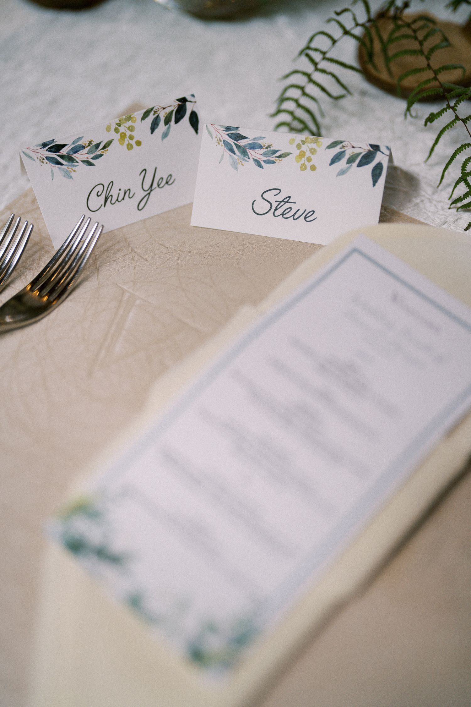 Wedding place cards with floral designs and elegant calligraphy on white paper.