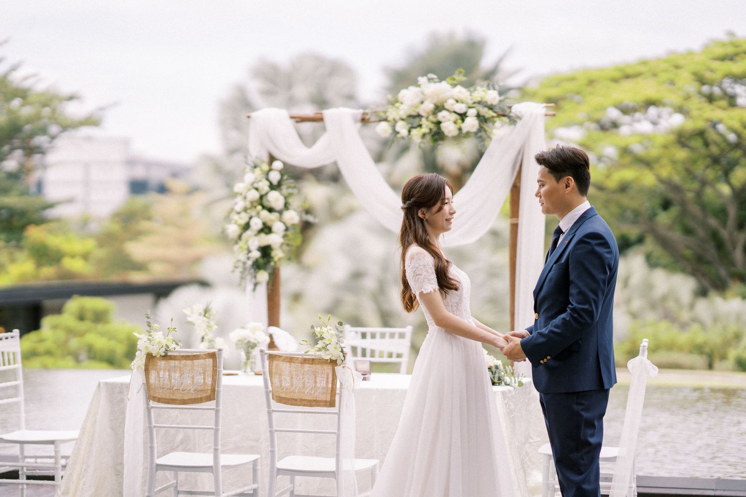 Outdoor wedding ceremony setup with white chairs and floral decorations.