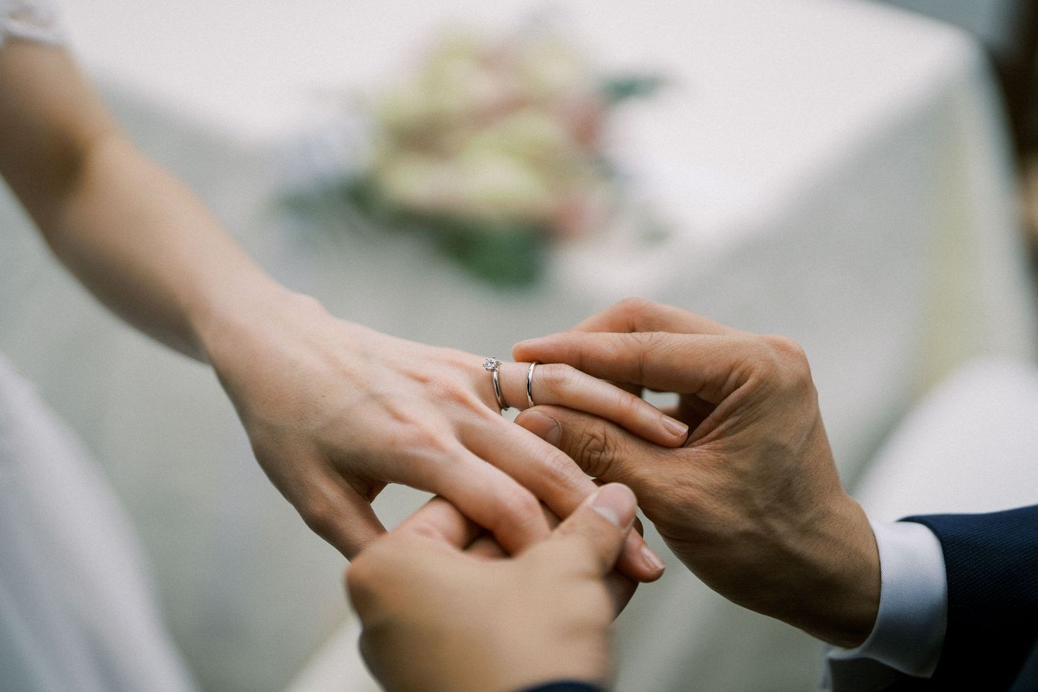 Close-up shot of hands exchanging wedding rings during ceremony.