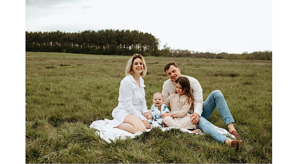 Wide panoramic shot of family spending time together in grass field.