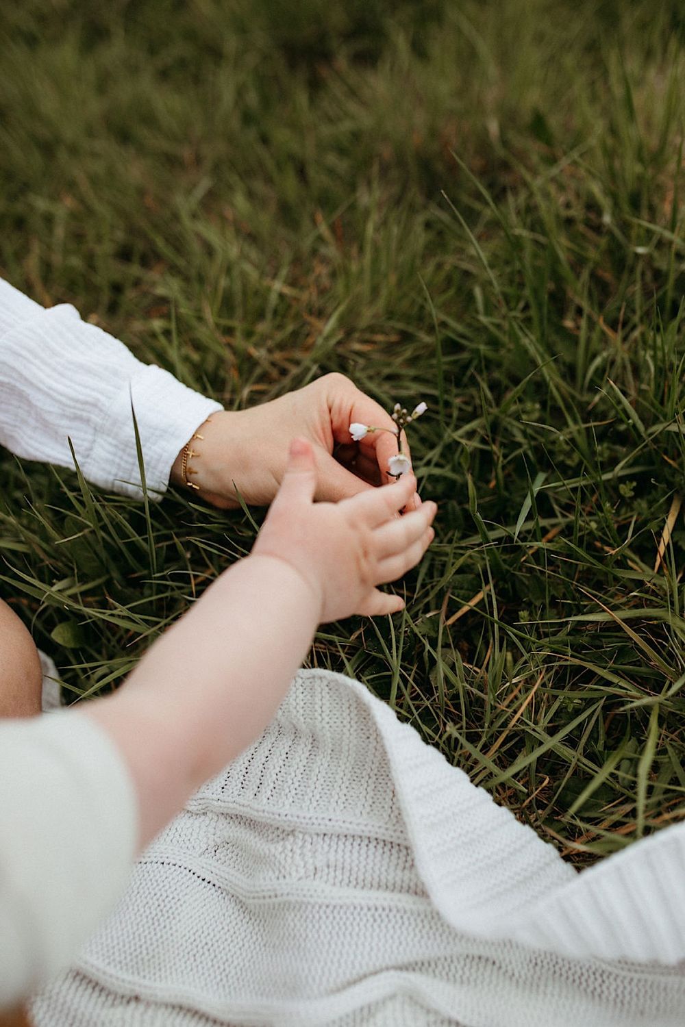 Close-up details of hands working on knitting or crochet project outdoors.