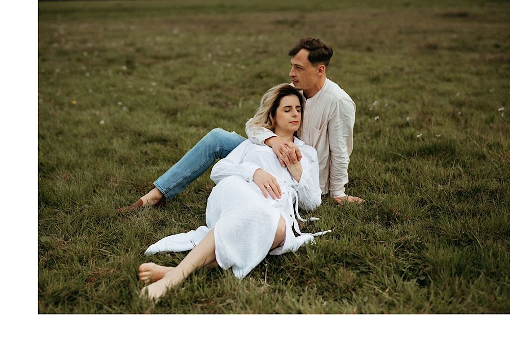 A couple playing and laughing together in a natural field setting.