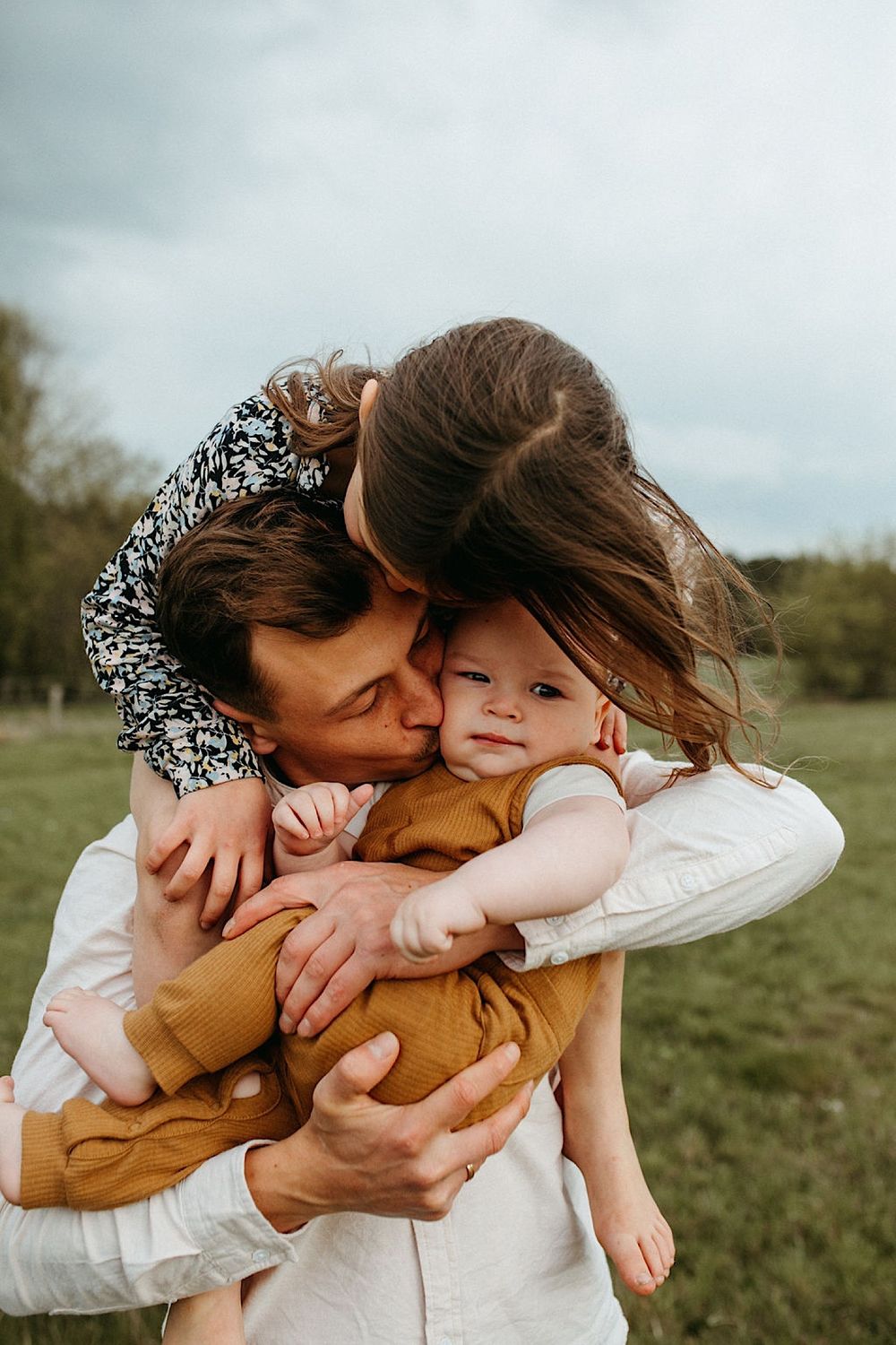 A tender family moment captured in a sunny field.