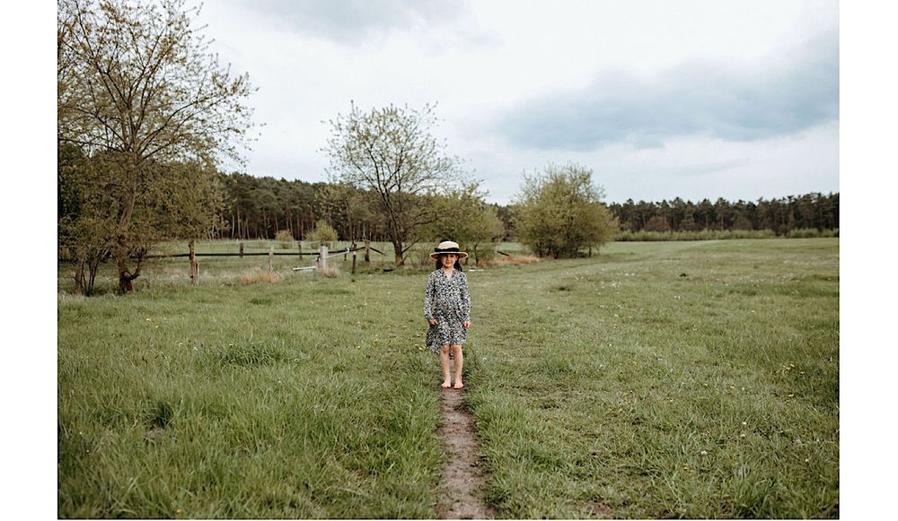 Couple walking hand in hand through a lush green meadow on an overcast spring day.