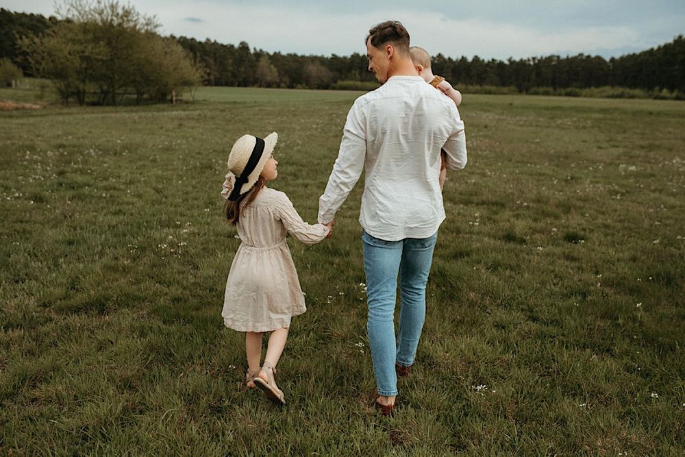 Couple taking a casual stroll together across a scenic grassy field with trees in background.