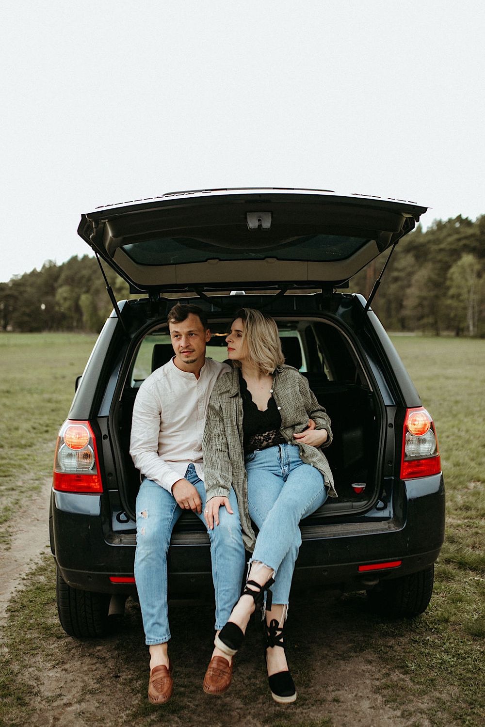 Couple sitting on the back of a black SUV sharing an intimate moment together.