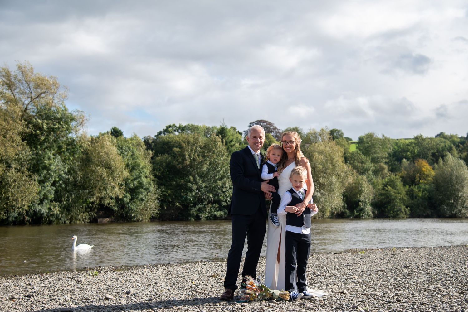 Wedding celebration at a scenic lakeside location with a white swan gliding across the water.